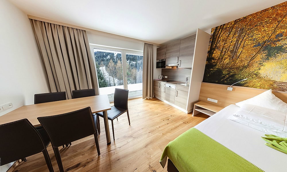 Entdecke_ Hotel Natürlich in Fiss, Tirol. Studio mit Küche, Estisch und Bett.