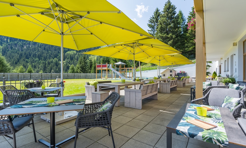 Entdecke_ Hotel Natürlich in Fiss, Tirol. Terrasse mit Sitzgelegenheiten und Schirme.