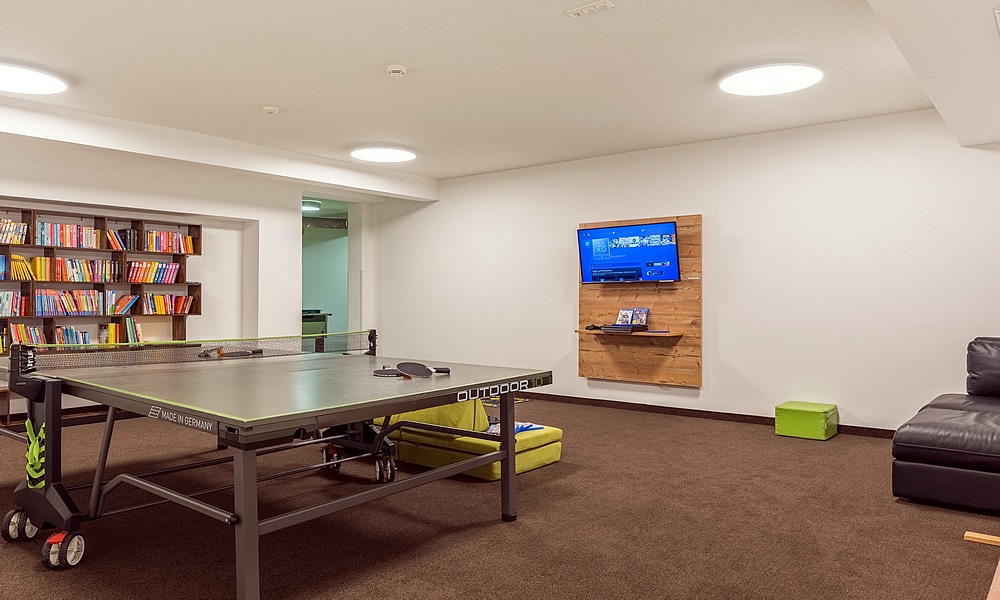 Spielzimmer in Natürlich. Hotel mit Charakter in Tirol - Österreich. Tischtennis, Flatscreen und Bücherregal.
