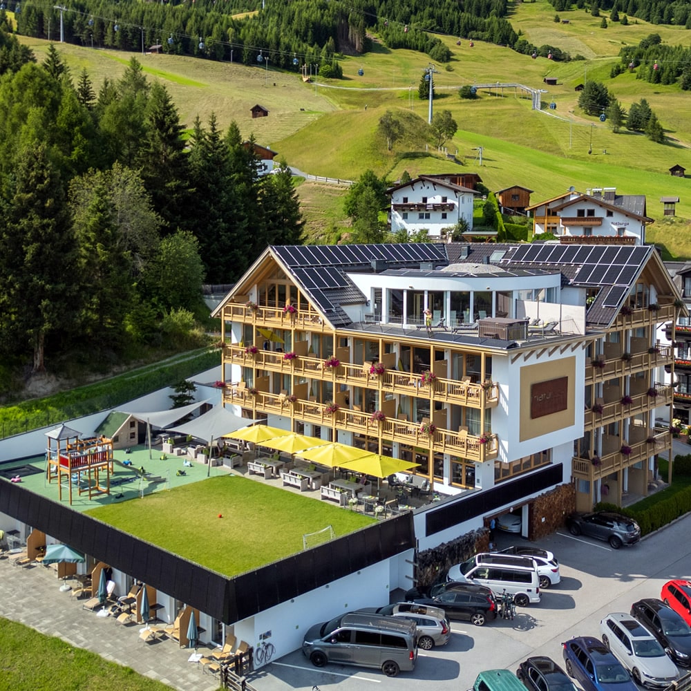 Südansicht von Natürlich. Hotel in Fiss - Tirol. Terrasse - Spielpatz und Wiese.